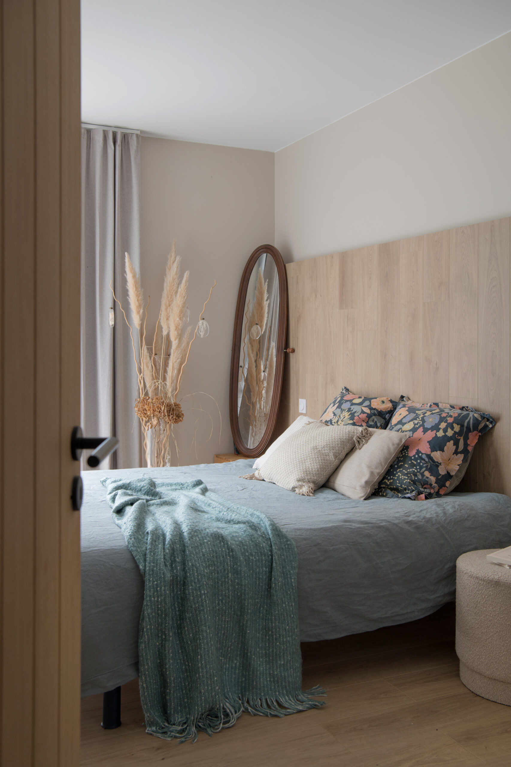 vue du couloir sur la suite parentale avec lit adossé à une tête de lit en bois et ouvertures en angle sur le jardin