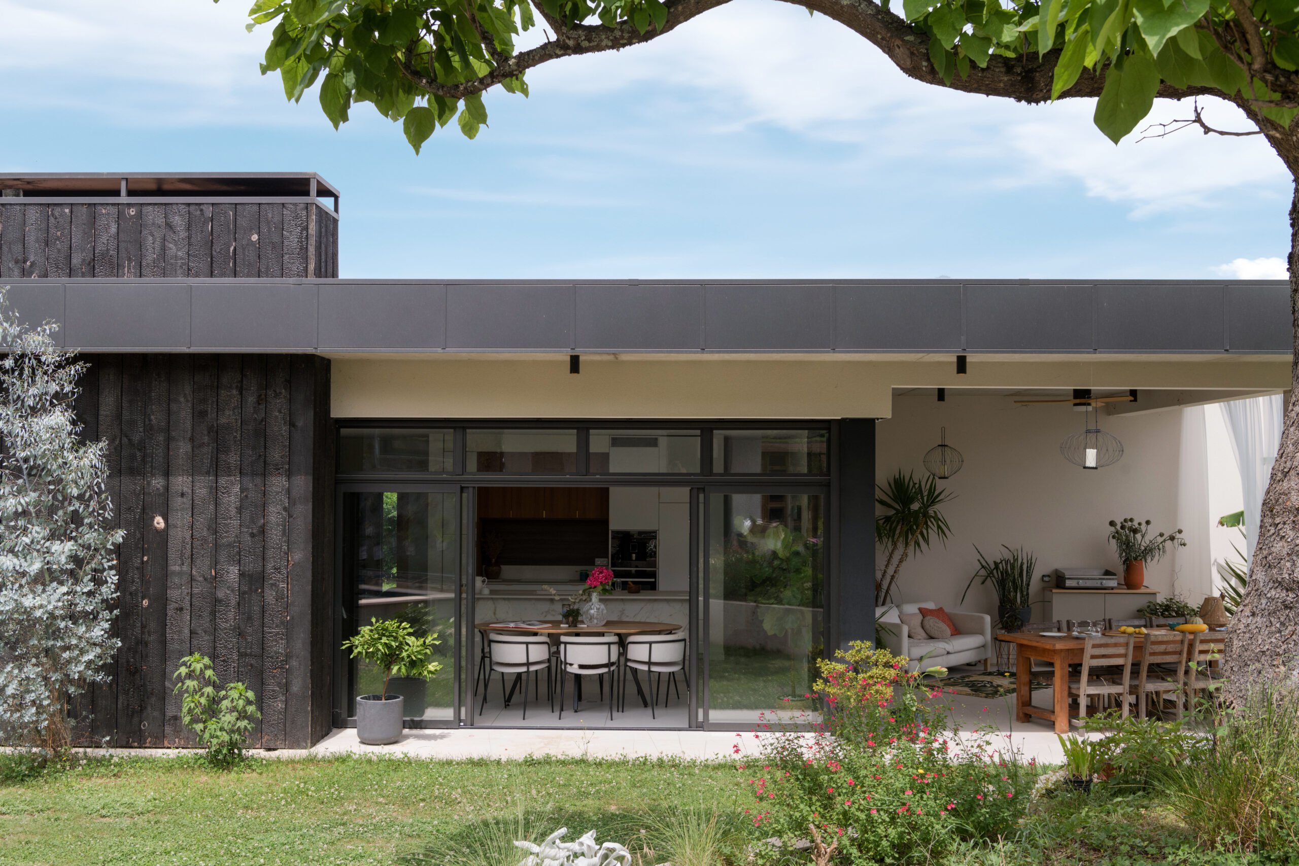 Villa contemporaine avec façade en bois brulé et terrasse couverte.